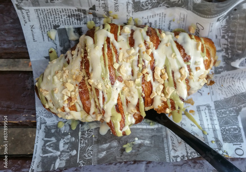 Croissant pastry with vanilla cream on top placed on newspaper