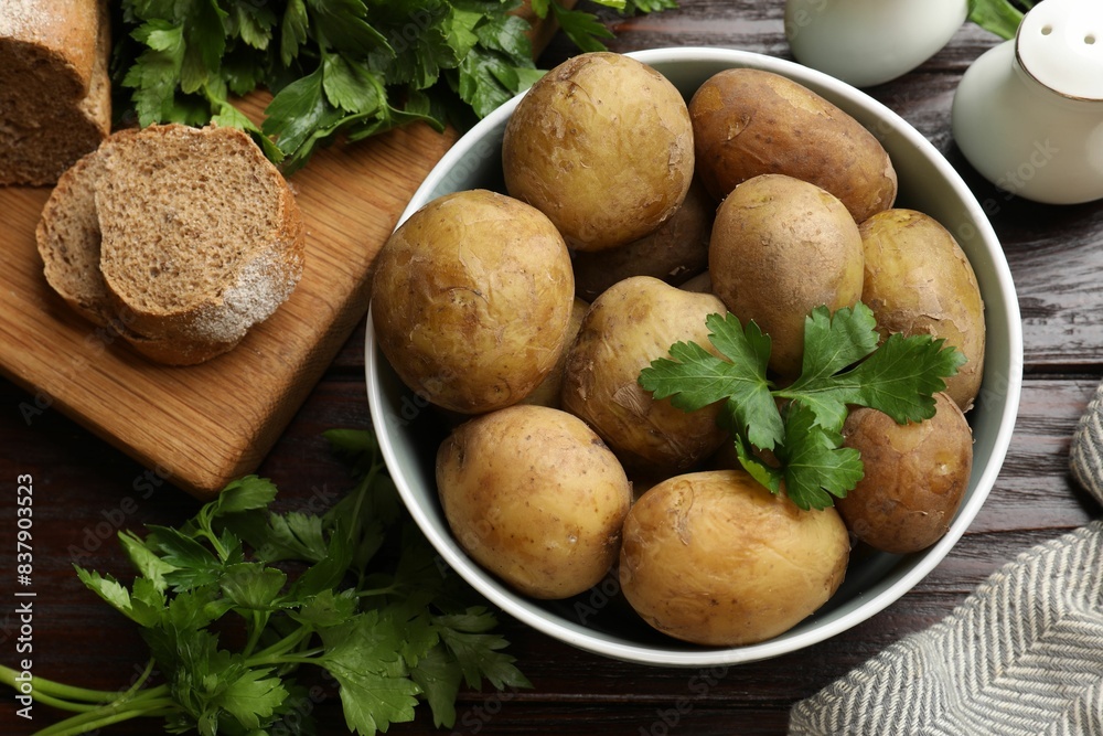 Boiled young potatoes in bowl, parsley and bread on wooden table, top view Boiled young potatoes in bowl, parsley and bread on wooden table, top view