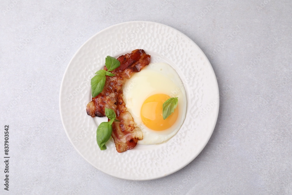 Fried egg, bacon and basil on light grey table, top view Fried egg, bacon and basil on light grey table, top view