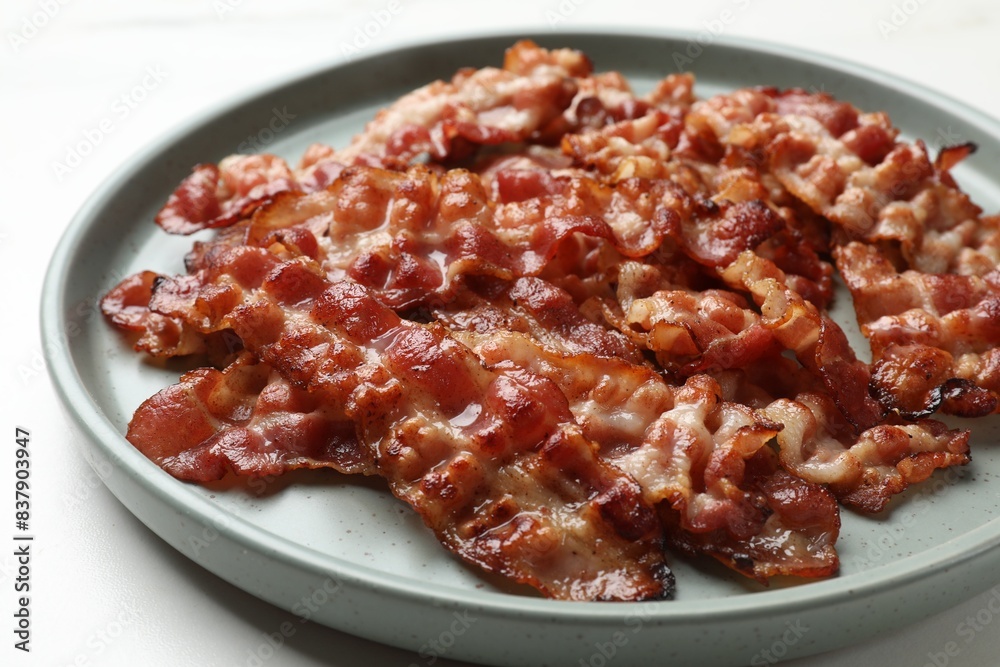 Slices of tasty fried bacon on white table, closeup