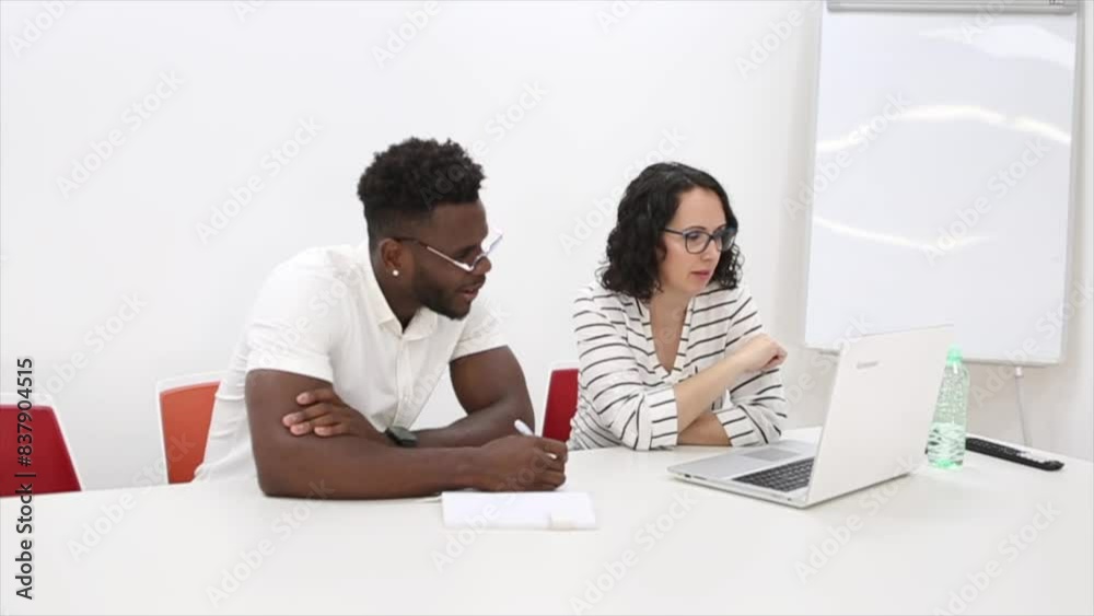 Two colleagues are working together in an office setting, using a laptop and smartphone for their project. Two colleagues are working together in an office setting, using a laptop and smartphone for their project.