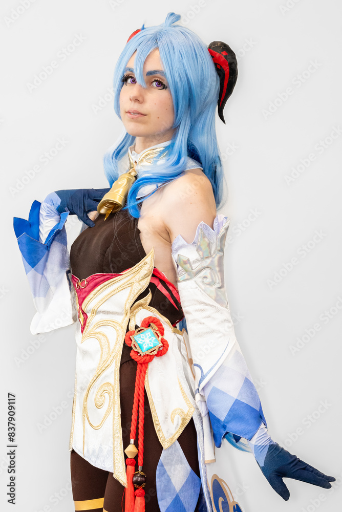 Female cosplayer with blue hair and an elaborate dress posing against a neutral background Female cosplayer with blue hair and an elaborate dress posing against a neutral background