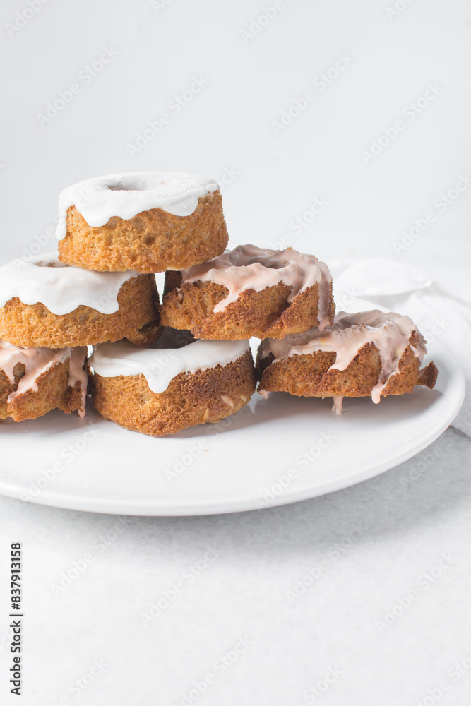 Iced mini bundt cakes on a white plate, vanilla bundlette with a clementine segment on a plate, small vanilla bundt cakes with an icing glaze Iced mini bundt cakes on a white plate, vanilla bundlette with a clementine segment on a plate, small vanilla bundt cakes with an icing glaze