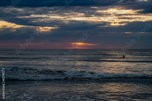 Sunrise in the Ocean with Surfers