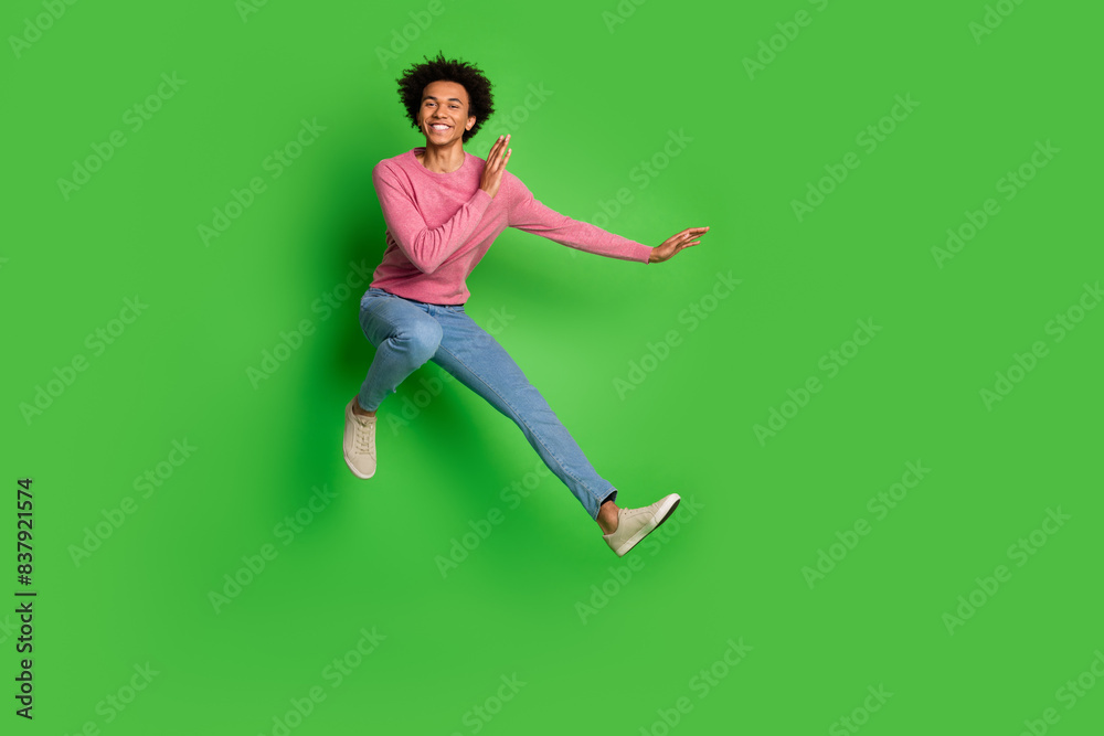 Full length photo of cheerful positive guy dressed pink pullover jumping high enjoy karate emtpy space isolated green color background