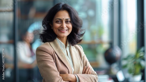 a mature smiling indian businesswoman is standing in the office