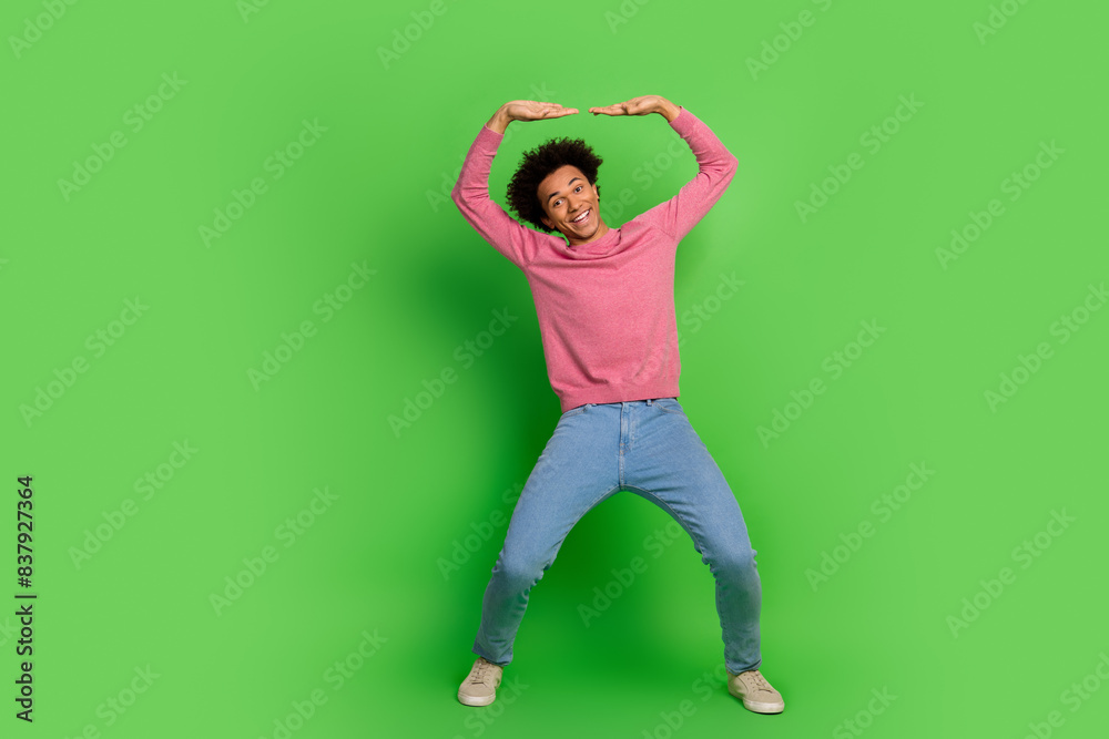 Full length photo of cheerful positive guy dressed pink pullover rising up emtpy space isolated green color background Full length photo of cheerful positive guy dressed pink pullover rising up emtpy space isolated green color background