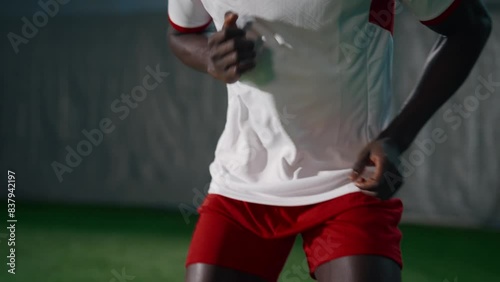 African American athlete training in football club, jumping and run exercise for developing endurance. Young black sportsman in sportive uniform exercising in indoor soccer stadium, portrait in motion photo