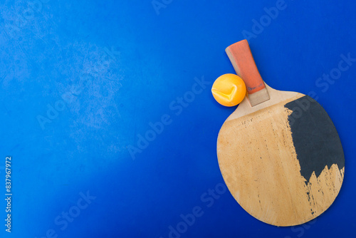 old pingpong rackets and a dented ball on a blue pingpong table © Freer