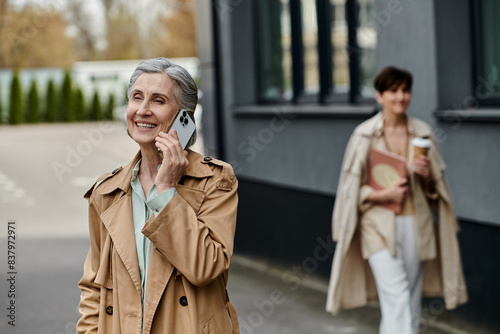 Woman chatting on phone while strolling along street with her partner.