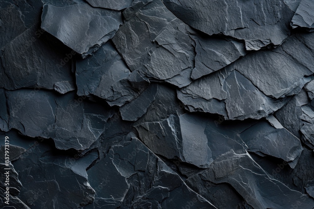 A close-up view of a dark-colored rock wall with textured surface A close-up view of a dark-colored rock wall with textured surface