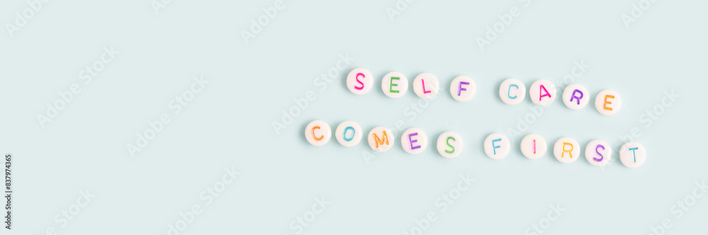 Self care comes first. Banner with quote made of round beads with letters on a blue background. Place for text. Self care comes first. Banner with quote made of round beads with letters on a blue background. Place for text.