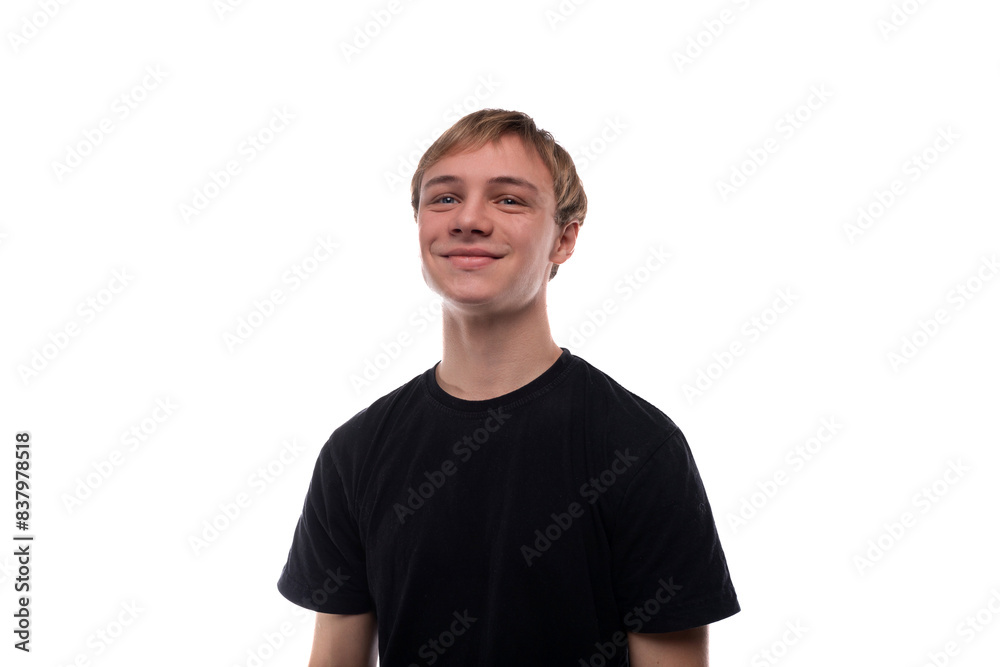 Fototapeta premium A handsome young man with blond hair dressed in a black T-shirt looks to the side