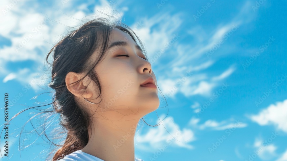 Beautiful Asian woman with clear skin against a blue sky background Beautiful Asian woman with clear skin against a blue sky background
