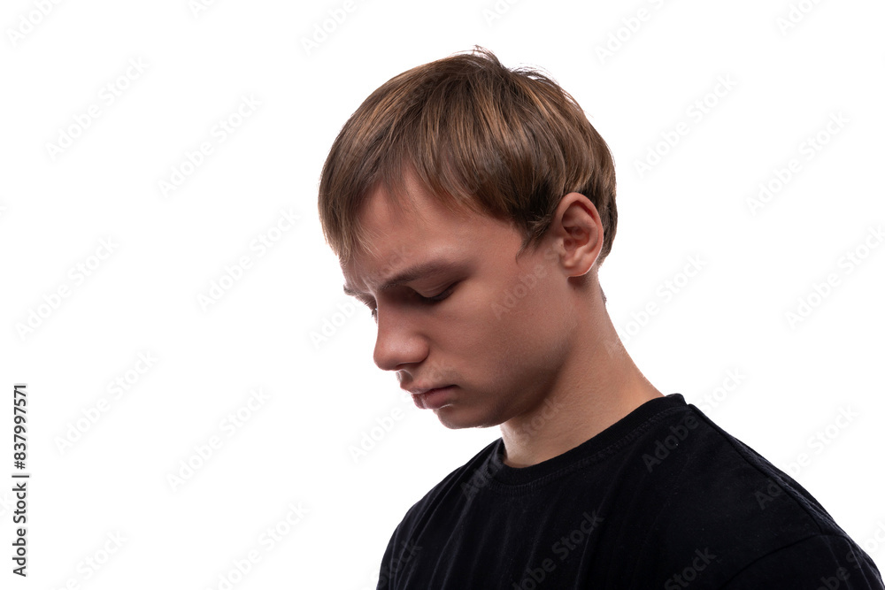 Handsome Caucasian blond teenager guy in a black T-shirt is upset because of problems Handsome Caucasian blond teenager guy in a black T-shirt is upset because of problems