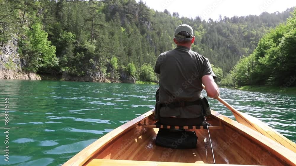 Rear view of man paddling canoe on the lake Rear view of man paddling canoe on the lake