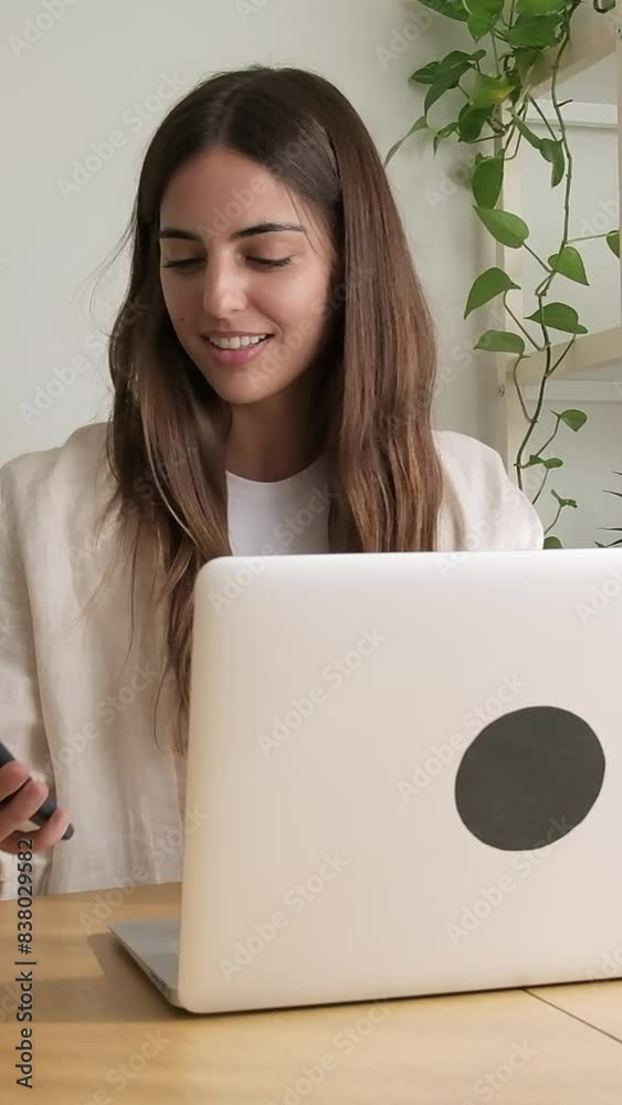 Vertical video of young woman working at home office. Happy female entrepreneur using laptop. 