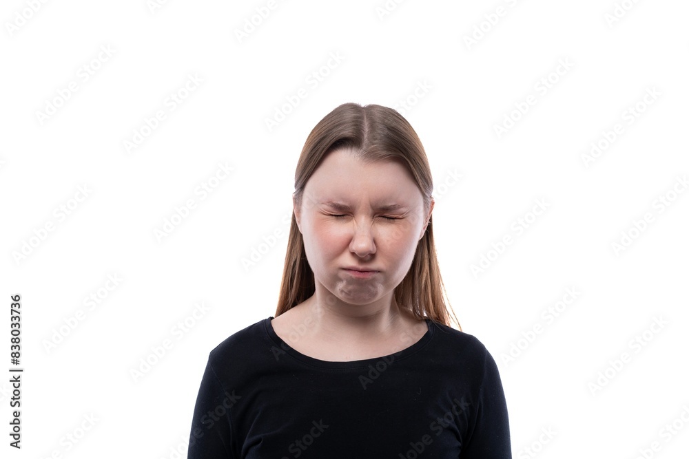 A school-age girl dressed in black clothes closed her eyes on a white background A school-age girl dressed in black clothes closed her eyes on a white background