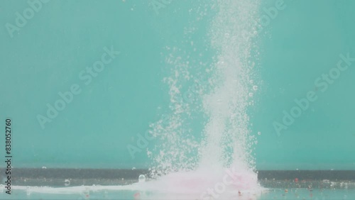 A one white round effervescent pill on a turquoise background falls into the water. Two tablets lie at the bottom of the container, dissolve, fizz to form bubbles and powder. The concept of testing