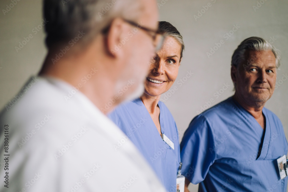 Happy female senior doctor talking with male colleagues in hospital Happy female senior doctor talking with male colleagues in hospital