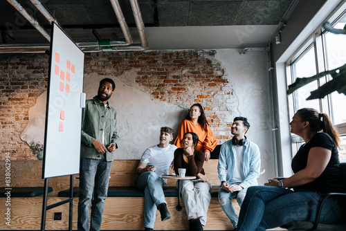 Male business professional doing team meeting with colleagues sitting at office photo