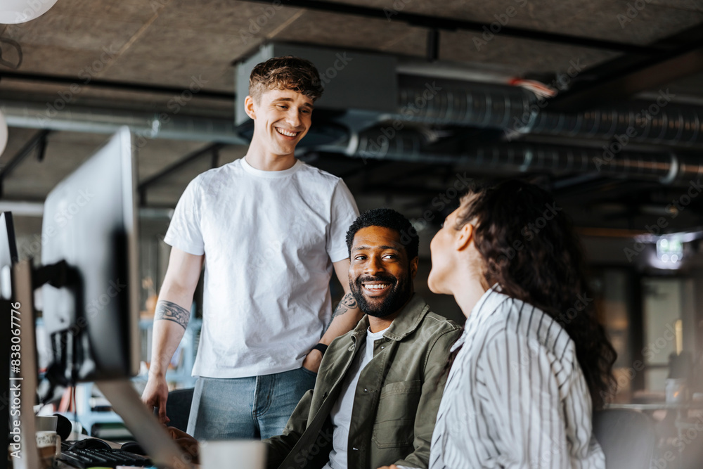 Smiling male entrepreneurs talking with female colleague at office Smiling male entrepreneurs talking with female colleague at office