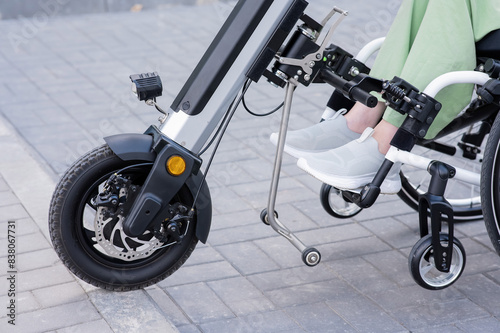 A faceless woman in a wheelchair with an assistive device for manual control. Electric handbike. 