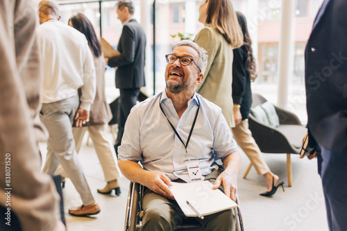 Smiling male entrepreneur with disability sitting on wheelchair during seminar at convention center photo