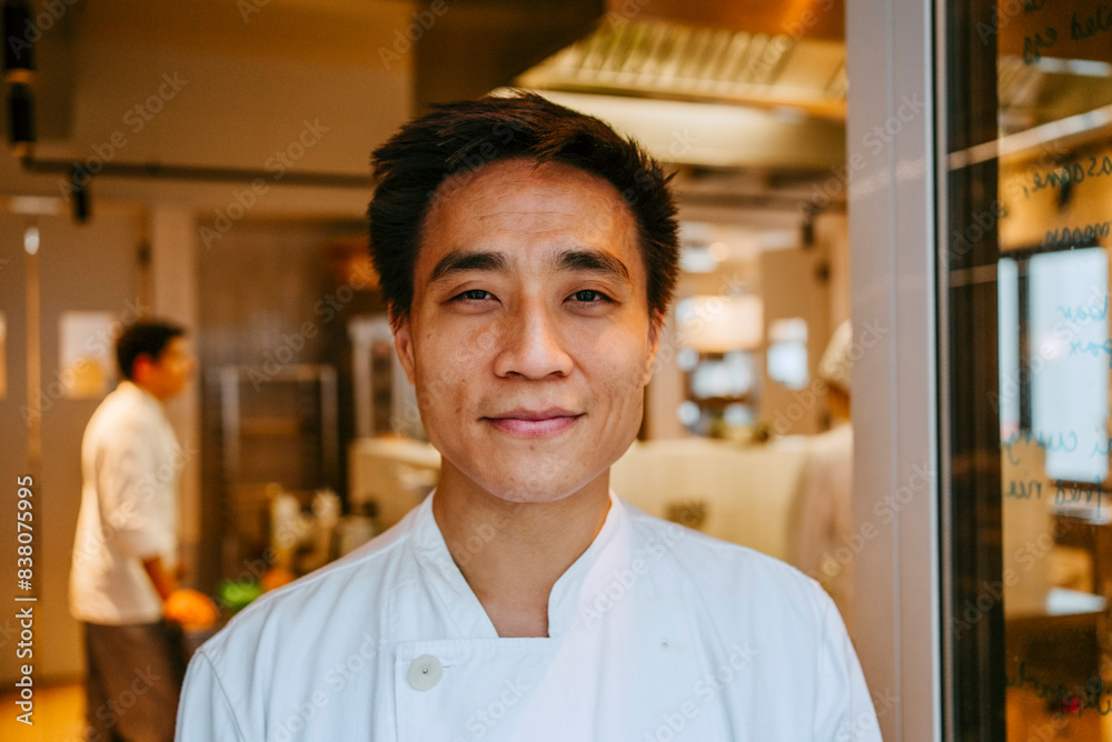 Close-up of smiling male chef standing at door in commercial kitchen Close-up of smiling male chef standing at door in commercial kitchen