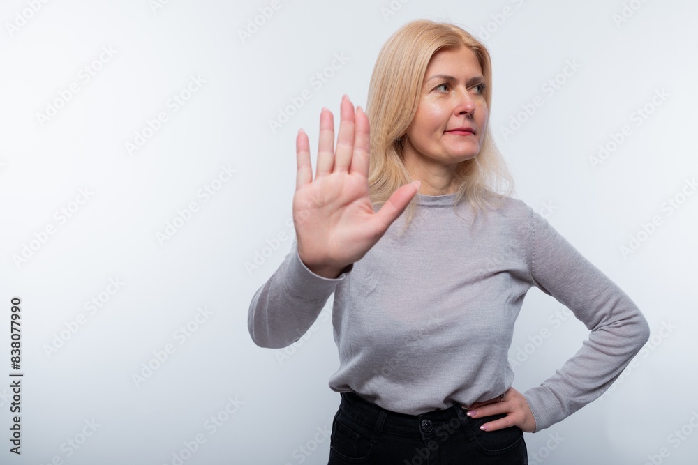 Mature blonde woman doubts and gesticulates against a background with copy space Mature blonde woman doubts and gesticulates against a background with copy space