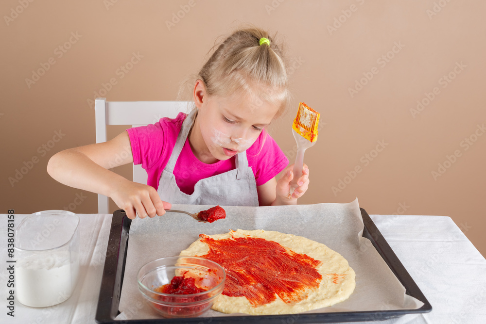Girl spreading tomato sauce on pizza dough, step 2. Yeast-free pizza, homemade, handmade, DIY pizza. Girl spreading tomato sauce on pizza dough, step 2. Yeast-free pizza, homemade, handmade, DIY pizza.