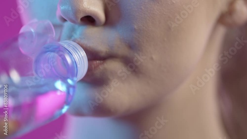 Makro zbliżenie ust kobiety pijącej wodę z plastikowej butelki z dzióbkiem na lazurowym tle — slow motion 4K, orzeźwienie, naturalność i kobiecy detal