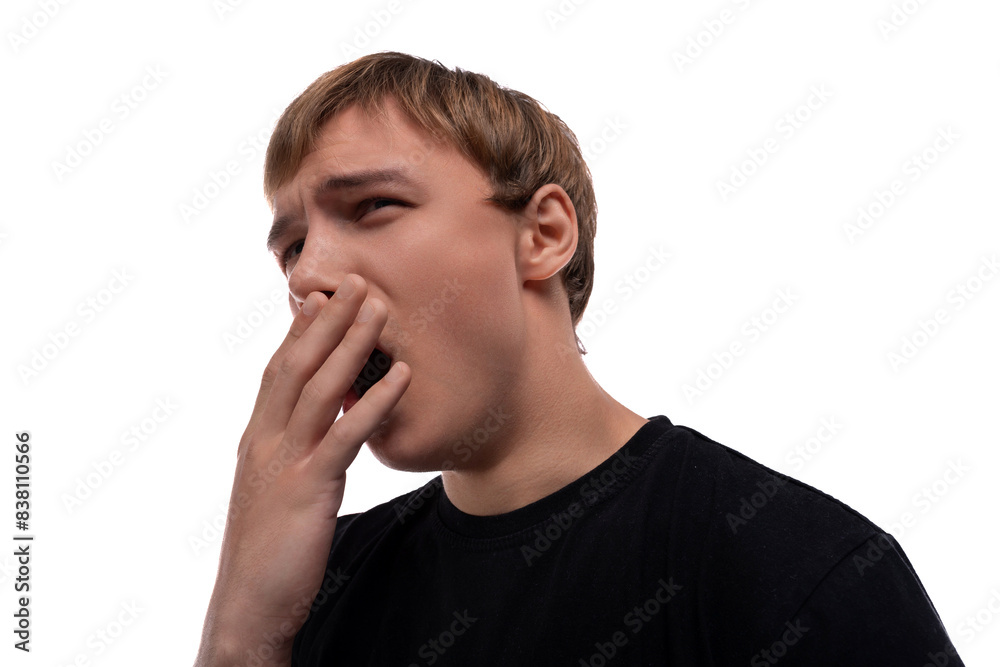 Handsome Caucasian blond teenager guy in a black T-shirt yawns cutely Handsome Caucasian blond teenager guy in a black T-shirt yawns cutely