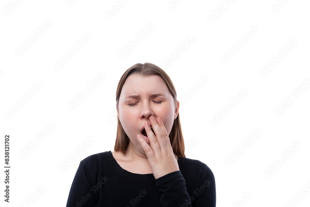 Cute school age girl dressed in black clothes yawns on a white background Cute school age girl dressed in black clothes yawns on a white background