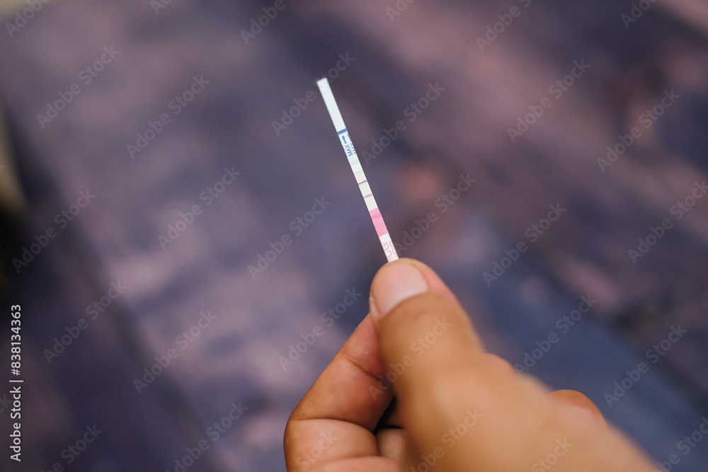 Woman hand holding positive pregnancy test strips on wood background Woman hand holding positive pregnancy test strips on wood background
