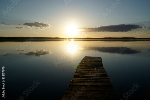 Wooden footbridge and sun reflecting in water at sunset