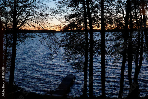 Fototapeta Naklejka Na Ścianę i Meble -  Sunset over lake with trees at shore