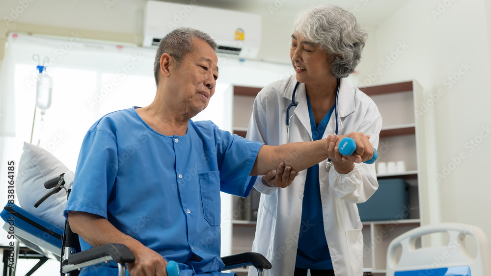 Elderly Asian man doing physical therapy with support from a senior female therapist nurse. Elderly man using elastic band to exercise for patient in home nursing, health care concept. Elderly Asian man doing physical therapy with support from a senior female therapist nurse. Elderly man using elastic band to exercise for patient in home nursing, health care concept.