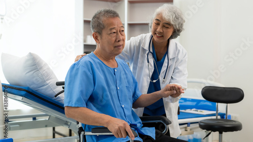 Elderly Asian man doing physical therapy with support from a senior female therapist nurse. Elderly man using elastic band to exercise for patient in home nursing  health care concept.