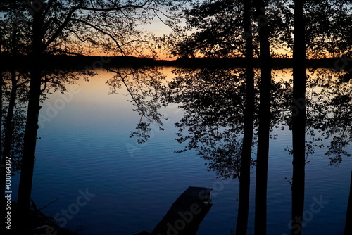 Fototapeta Naklejka Na Ścianę i Meble -  Sunset over lake with trees at shore