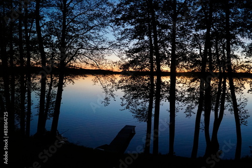 Fototapeta Naklejka Na Ścianę i Meble -  Sunset over lake with trees at shore