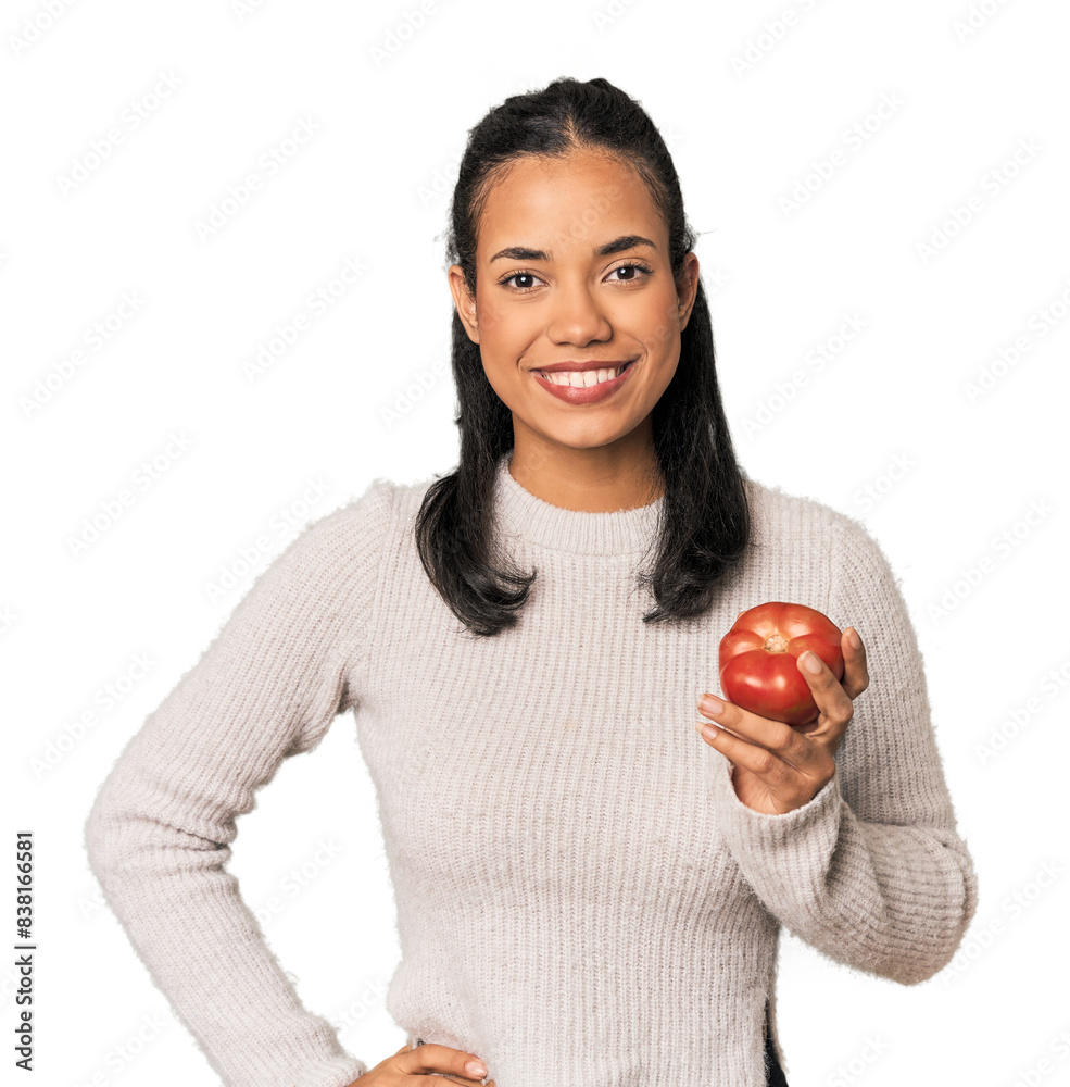 Young Filipina holding a tomato showing a copy space on a palm and holding another hand on waist. Young Filipina holding a tomato showing a copy space on a palm and holding another hand on waist.