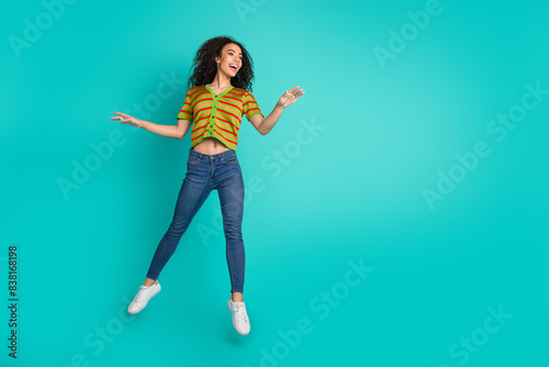 Full size photo of attractive young woman jump graceful dressed stylish striped clothes isolated on aquamarine color background