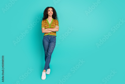 Full body photo of pretty young girl look empty space crossed hands wear trendy striped outfit isolated on aquamarine color background