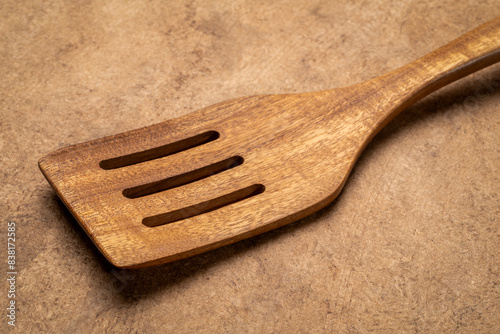 drainer spoon - wooden kitchen cooking utensils on textured bark paper photo