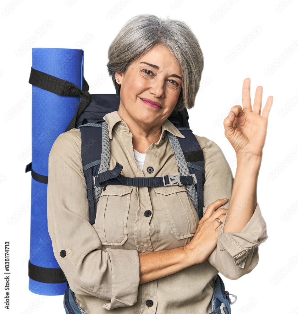 Caucasian mid-age female with hiking gear winks an eye and holds an okay gesture with hand. Caucasian mid-age female with hiking gear winks an eye and holds an okay gesture with hand.