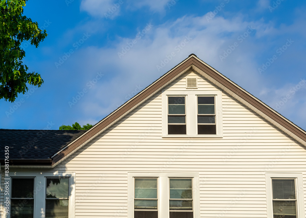 Upper portion of a family house with white siding against a blue sky with scattered clouds, Brighton, Massachusetts, USA