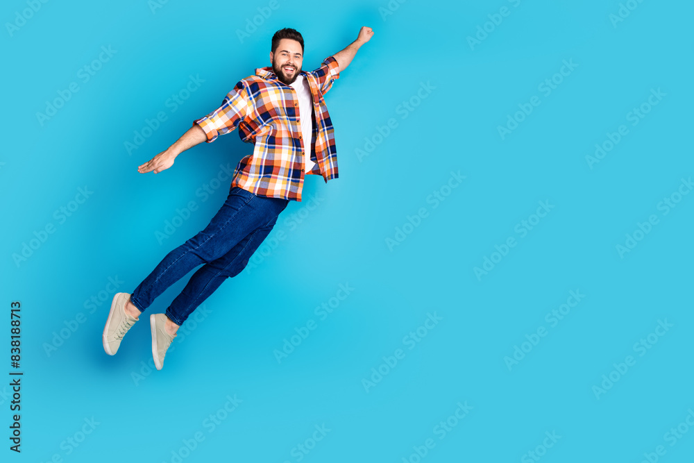 Full size photo of nice young man jump fly empty space wear shirt isolated on blue color background Full size photo of nice young man jump fly empty space wear shirt isolated on blue color background