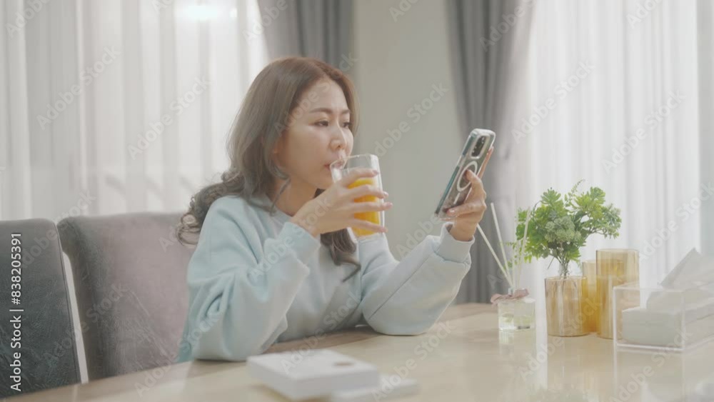 Women are playing with their mobile phones on the sofa and the dining table and drinking coffee or orange juice at the same time. Women are playing with their mobile phones on the sofa and the dining table and drinking coffee or orange juice at the same time.