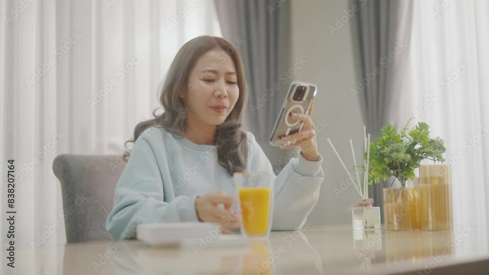Women are playing with their mobile phones on the sofa and the dining table and drinking coffee or orange juice at the same time. Women are playing with their mobile phones on the sofa and the dining table and drinking coffee or orange juice at the same time.